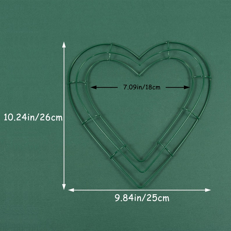 K&ouml;nnte beinhalten: Gr&uuml;ner, herzf&ouml;rmiger Kranzrahmen aus Metall mit zwei Schichten. Der Rahmen misst 10,24 Zoll mal 9,84 Zoll, oder 26 cm mal 25 cm.