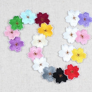 Puede incluir: Parches bordados con forma de flor en varios colores, incluyendo verde, rosa, morado y amarillo. Los parches tienen un borde blanco y un centro detallado. Ideales para proyectos de manualidades.