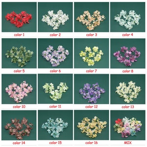 May include: Assortment of 16 colors of small artificial flowers, each color shown in a separate pile. The colors are red, white, beige, light blue, green, purple, yellow, pink, light pink, light green, lavender, white with green accents, brown, blue, cream, and pink with red accents.