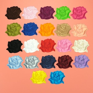 May include: Assortment of 25 iron-on rose patches in various colors, including black, white, red, blue, green, yellow, orange, and pink. Each patch features a detailed embroidered rose design.