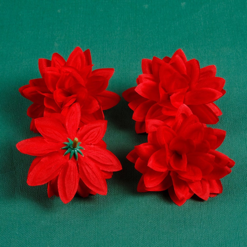 Puede incluir: Cuatro flores de poinsettia de fieltro rojo sobre un fondo verde. Las flores est&aacute;n dispuestas en dos pares.