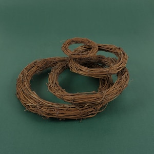 Puede incluir: Un conjunto de tres coronas de ramas marrones de diferentes tamaños, dispuestas en una pila. Las coronas están hechas de ramas naturales y son perfectas para decorar para las fiestas o para agregar un toque rústico a la decoración de tu hogar.