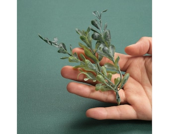 May include: A sprig of green artificial greenery with small, textured leaves.
