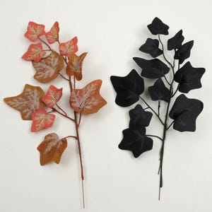 May include: Two artificial ivy stems. One stem features orange and brown leaves with white veining. The other stem has black leaves. Both stems have thin, brown branches and a wire base for easy placement.
