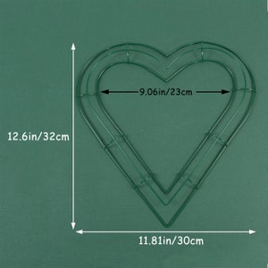 K&ouml;nnte beinhalten: Ein gr&uuml;ner, herzf&ouml;rmiger Kranzrahmen aus Metall mit einer H&ouml;he von 32 cm, einer Breite von 23 cm und einer Breite von 30 cm an der Unterseite.