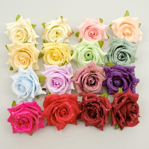 May include: A collection of artificial rose flower heads in various colors, including cream, yellow, pink, green, blue, purple, and red. Each rose has water droplets, and green leaves. These decorative flowers are suitable for crafts and floral arrangements.