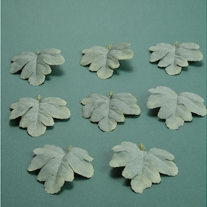 May include: Eight artificial green leaves with a slightly textured surface. The leaves are arranged in a grid pattern on a light blue background.