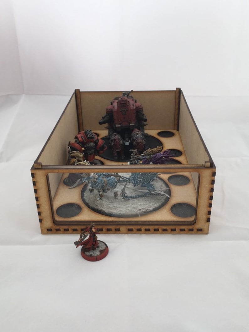 May include: A wooden box with a glass front, containing miniature figures and bases. The box has a brown wood finish and a black interior. The figures are painted in various colors, including red, blue, and purple.