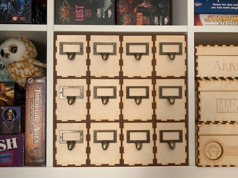 May include: A set of 12 wooden storage boxes with labels and metal handles. The boxes are arranged in a 3x4 grid and are all the same size. The boxes are a light wood color and have a natural finish.