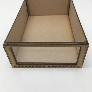 May include: A wooden box with a clear plastic window. The box is made of light brown wood and has a simple design.