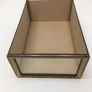 May include: A wooden display case with a clear glass front. The case is made of light brown wood and has a simple, rectangular design.