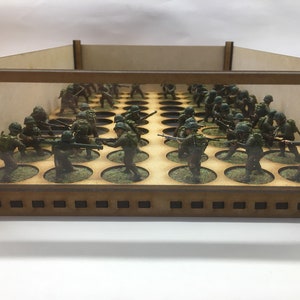 May include: A wooden display case with a clear front panel, showcasing a collection of miniature figures in military uniforms. The figures are arranged on circular bases and are positioned in a battle formation.