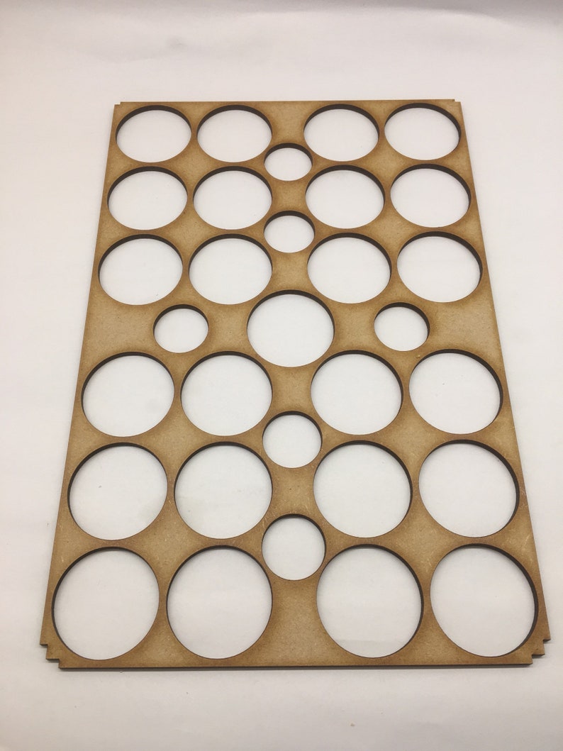 May include: A wooden board with a grid of circular cutouts of varying sizes. The board is light brown and has a natural wood finish.