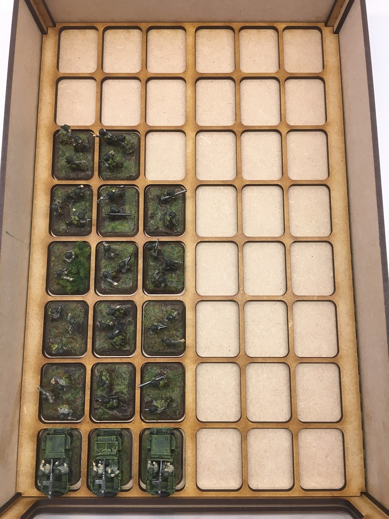 May include: A wooden storage box with a grid of compartments. The compartments are filled with miniature figures and vehicles, including soldiers, guns, and trucks. The figures are painted in camouflage colors.