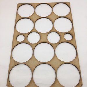 May include: A wooden paint palette with 14 circular cutouts of varying sizes. The palette is brown and has a smooth surface.