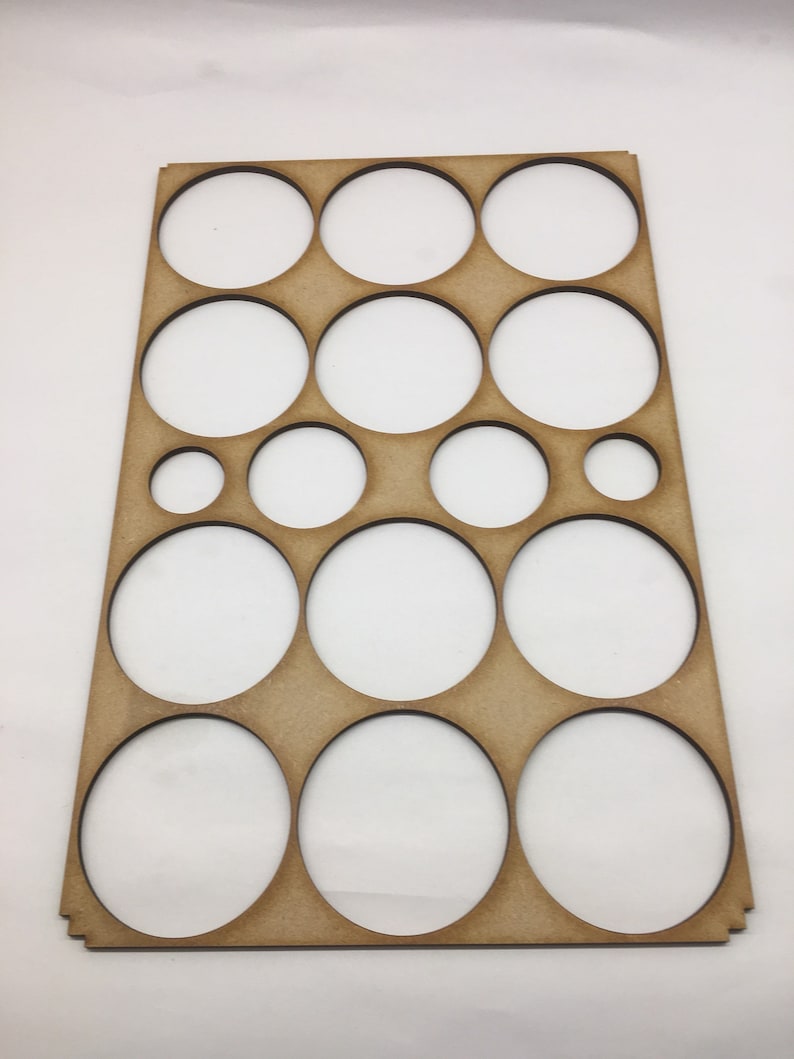 May include: A wooden paint palette with 14 circular cutouts of varying sizes. The palette is brown and has a smooth surface.