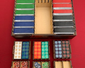 May include: A wooden organiser for a board game with multiple compartments for cards and dice. The organiser has a brown stain and includes compartments for different coloured dice and tokens.
