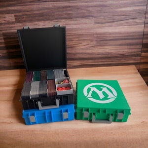 May include: Two black and blue card storage boxes with a green card storage box with the Magic: The Gathering logo on the front.