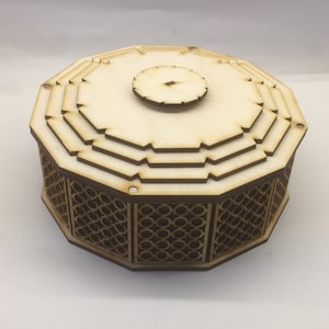 May include: A wooden octagonal box with a layered lid and a decorative lattice pattern around the bottom. The box is made of light wood and has a natural finish.