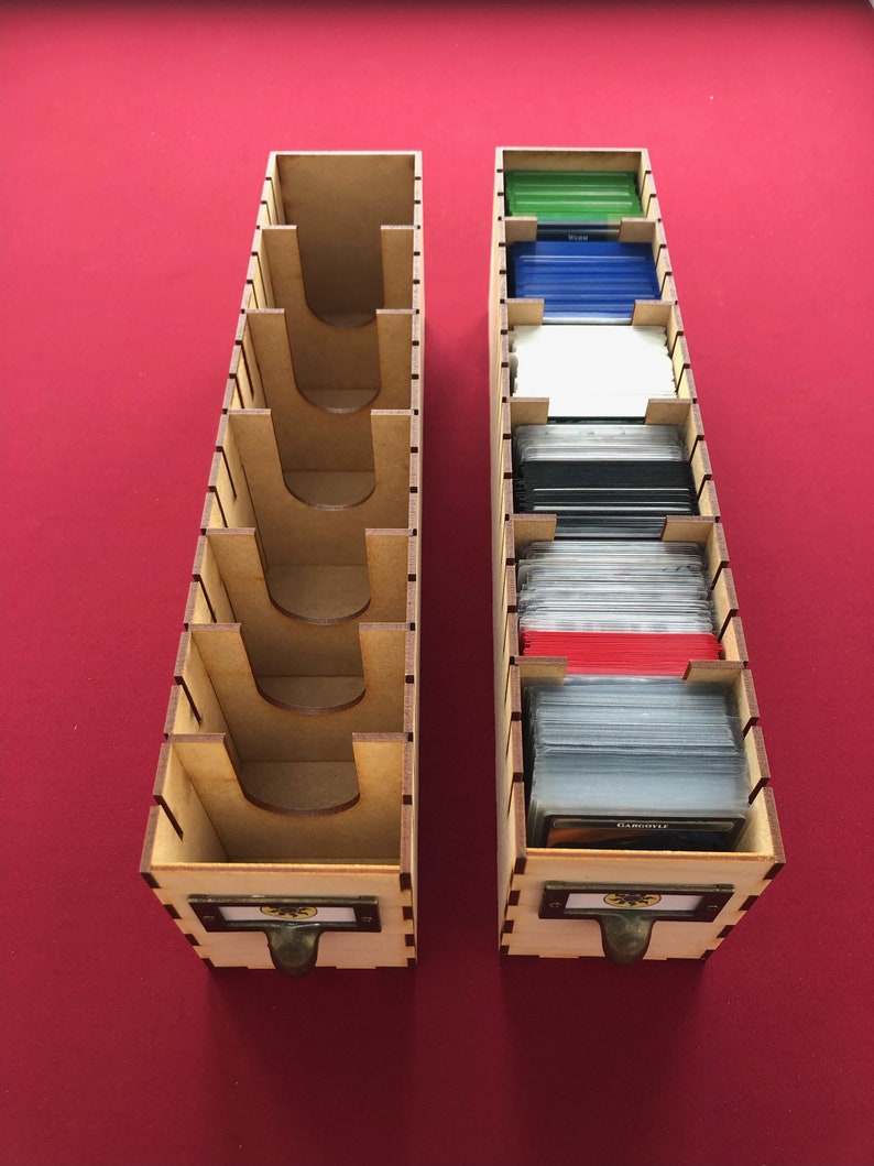 May include: Two wooden card storage boxes with dividers. The boxes are made of light brown wood and have a metal handle. The boxes are filled with cards of different colors.