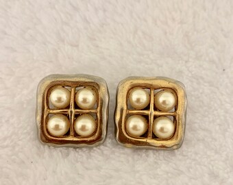 May include: A pair of gold and silver tone earrings with six faux pearls in a grid pattern.