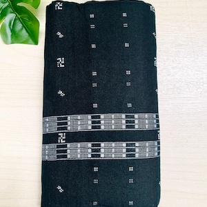 以下が含まれることがあります： 白の幾何学模様が施された黒い布。布は織り込まれた質感で、半分に折り畳まれています。