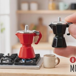 May include: Miniature red and black espresso makers with silver detailing. A small, beige ceramic mug is also present. The red espresso maker is on a miniature stove with a blue flame. The scene suggests a kitchen setting.