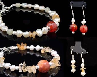 Könnte beinhalten: Schmuckset mit zwei Armbändern und zwei Paar Ohrringen. Die Armbänder sind aus weißen Perlen, kleinen Edelstein-Chips und einer großen rot-orangen Edelsteinperle gefertigt. Die Ohrringe haben ein ähnliches Design mit Perlen und rot-orangen Perlen.