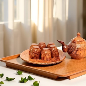 May include: A bamboo tea set comprising a teapot and six cups on a wooden tray. The teapot has a curved spout and handle. The cups are arranged on a round plate. The set is a warm brown colour.