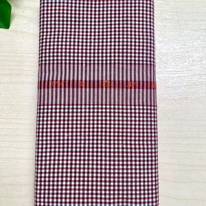 Puede incluir: Una tela a cuadros blancos y marrones con una fina franja roja y naranja.