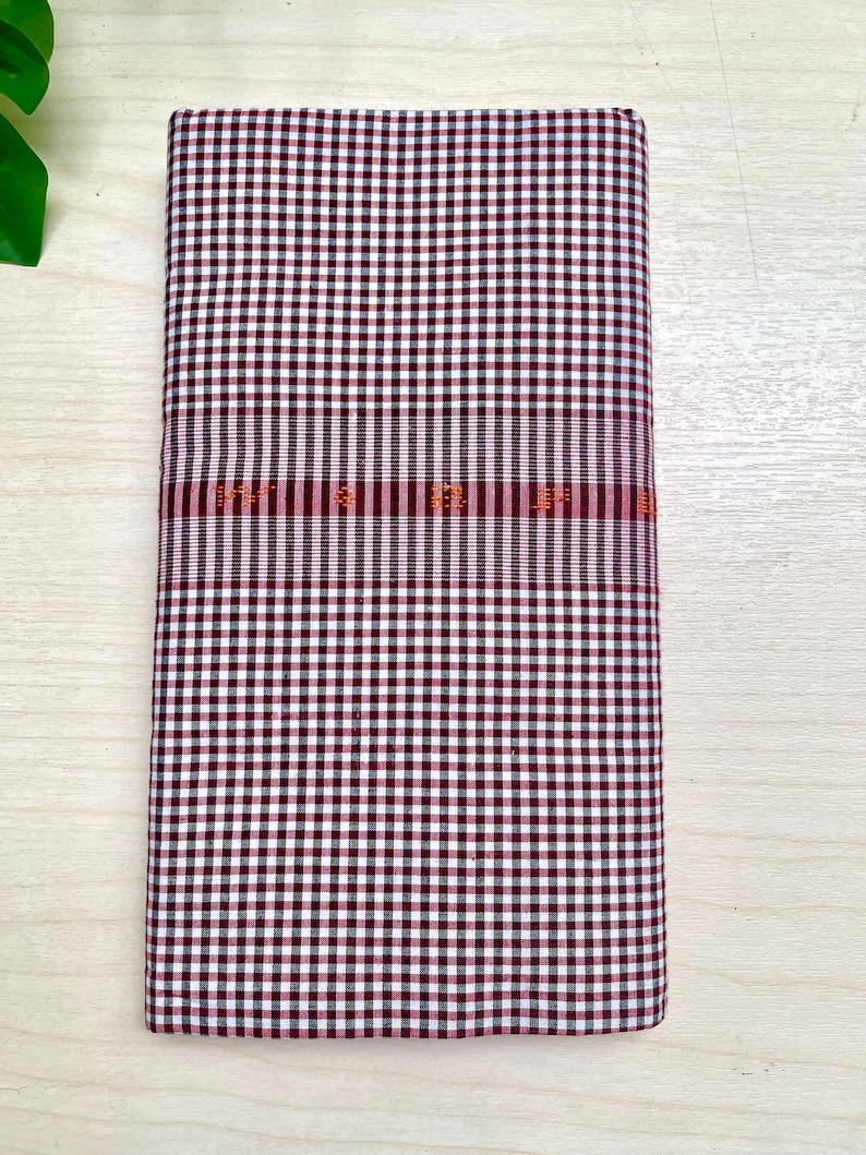 Puede incluir: Una tela a cuadros blancos y marrones con una fina franja roja y naranja.