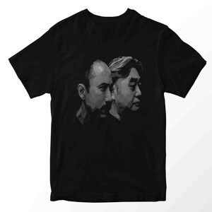 Könnte beinhalten: Schwarzes T-Shirt mit einem Graustufen-Porträt von zwei Männern im Profil. Die Illustration verwendet Schattierungen, um einen realistischen Effekt zu erzielen. Das T-Shirt ist ein klassischer Rundhalsausschnitt.