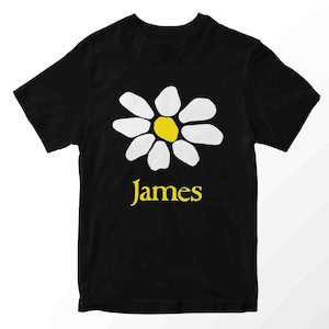 May include: Black t-shirt with a daisy design. The flower has white petals and a yellow centre. The name "James" is printed in yellow beneath the flower. A simple, casual tee.