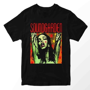 May include: Black t-shirt featuring a graphic of a woman with red star accents and the band name "SOUNDGARDEN" in red block letters. The woman has long dark hair and is set against a background of yellow and red stars.