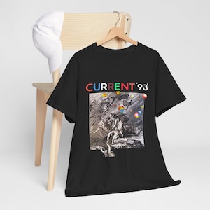 Puede incluir: Camiseta negra con un estampado gráfico de una ilustración en blanco y negro de personas en una escena caótica. El texto "CURRENT '93" está impreso en colores arcoíris sobre la ilustración.