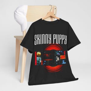 May include: Black t-shirt featuring the text "Skinny Puppy" in white lettering and a red and black graphic image. The graphic image includes the text "Ja" in white lettering.