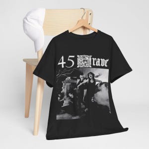 May include: Black t-shirt with a graphic print of a band called "45 Grave". The graphic features a black and white image of a band performing on stage in front of a tombstone.