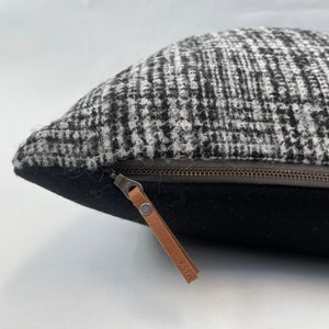 Könnte beinhalten: Ein Kissen mit schwarz-weißem Muster und einem braunen Leder-Reißverschluss-Zipper, auf dem "HISA" steht.