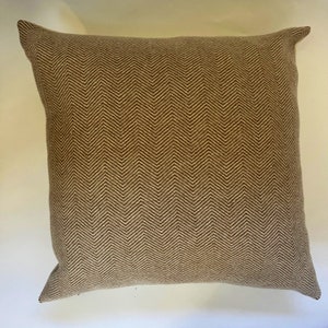 May include: A brown and beige throw pillow with a herringbone pattern.