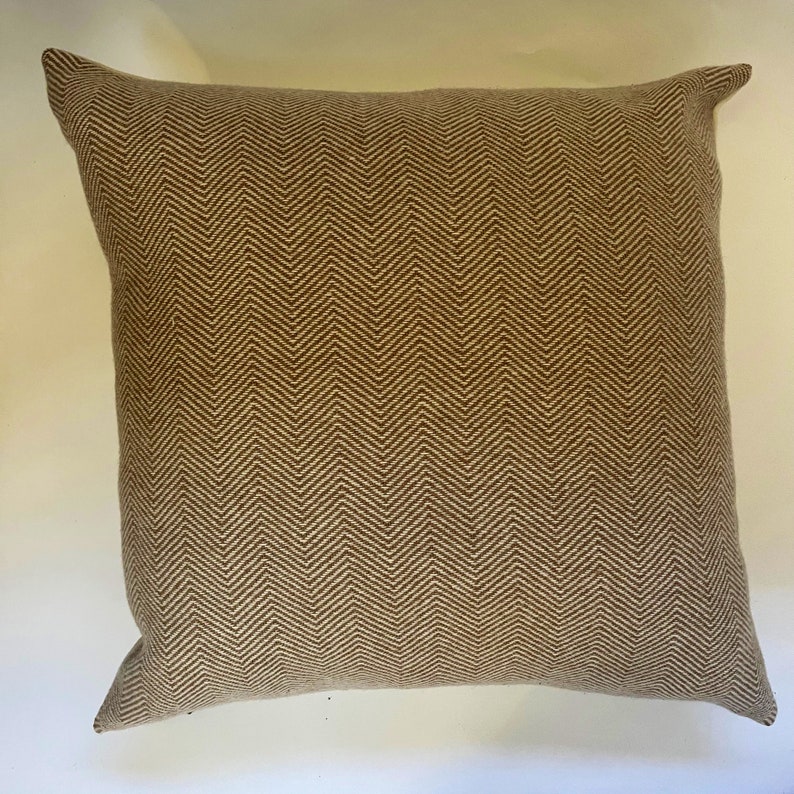 May include: A brown and beige throw pillow with a herringbone pattern.