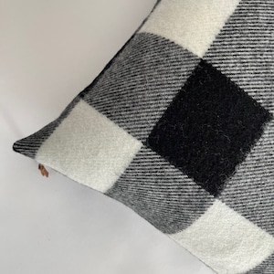 May include: Black and white checkered throw pillow with a soft, fuzzy texture.