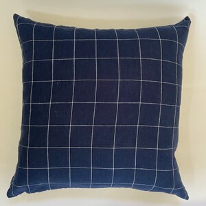 May include: A navy blue throw pillow with a white grid pattern.