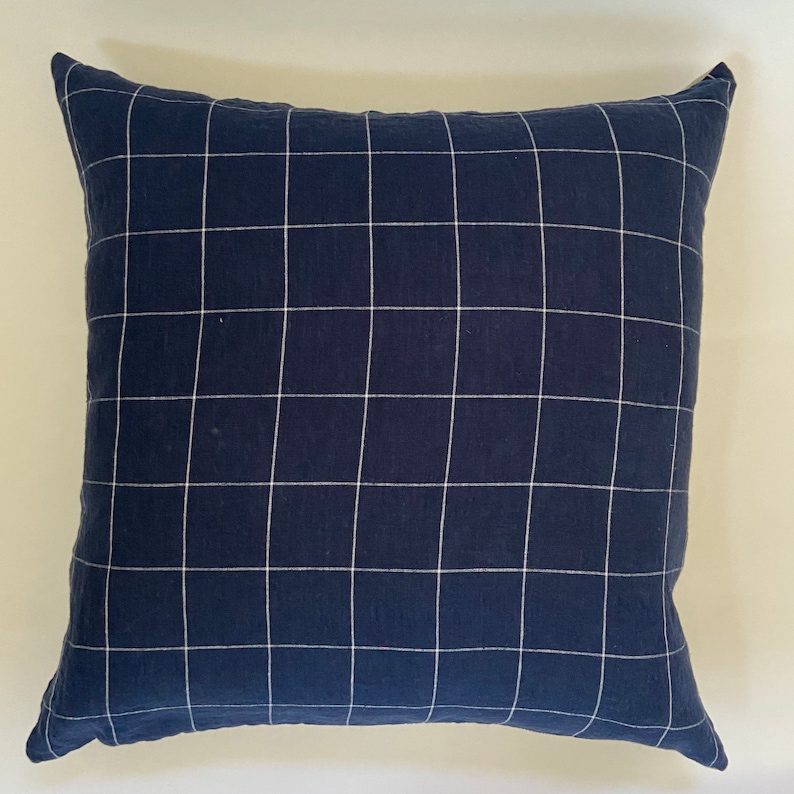 May include: A navy blue throw pillow with a white grid pattern.