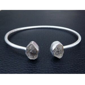 May include: A silver bangle bracelet with two clear quartz crystal ends.