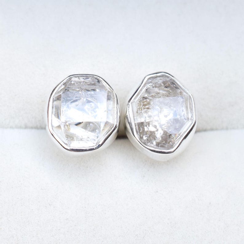 May include: A pair of silver earrings with clear, faceted, octagonal gemstones.