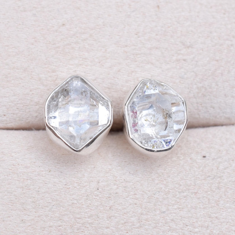 May include: A pair of silver earrings with clear, faceted, octagonal-shaped gemstones.