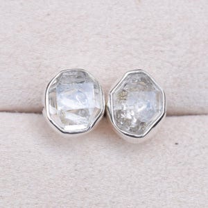 May include: A pair of silver earrings with clear, faceted, octagonal-shaped gemstones.
