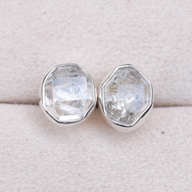 May include: A pair of silver earrings with clear, faceted, octagonal-shaped gemstones.