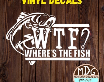 May include: White vinyl decal with a fish silhouette and the text "WTF? Where's the Fish" with a fishing hook. The decal is on a wood background. The decal is from Montana Decal Gal Decals & Stickers.