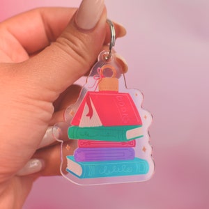 May include: A clear acrylic keychain with a stack of colorful books. The top book is red and says "BOOKS" on the spine. The keychain has a silver ring.